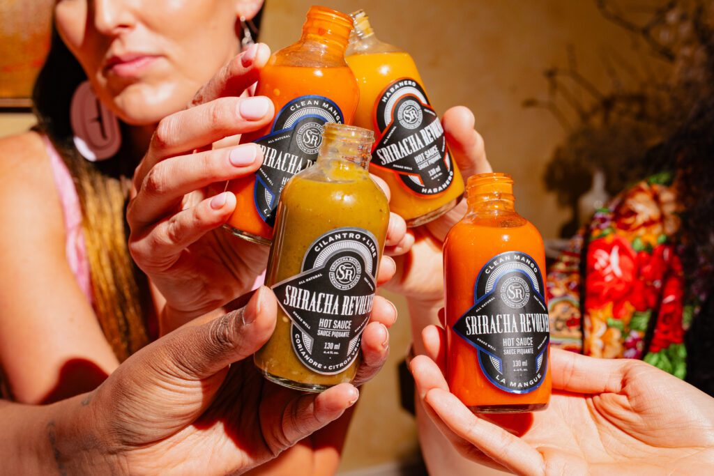 Group of people sharing a meal and holding bottles of hot sauce together