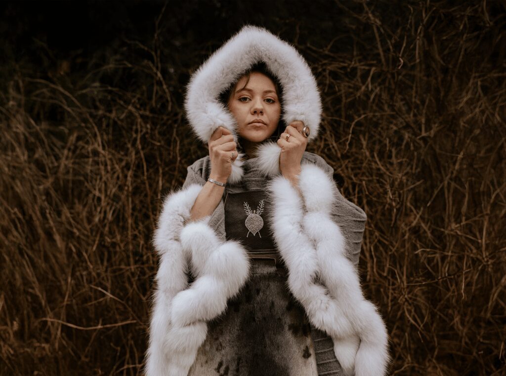 A woman dressed in Naomi's Bourque's fur poncho standing against a background of dark grass
